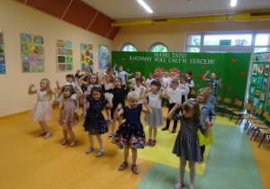 Dzieci tańczą, unoszą ręce nad głowami.
